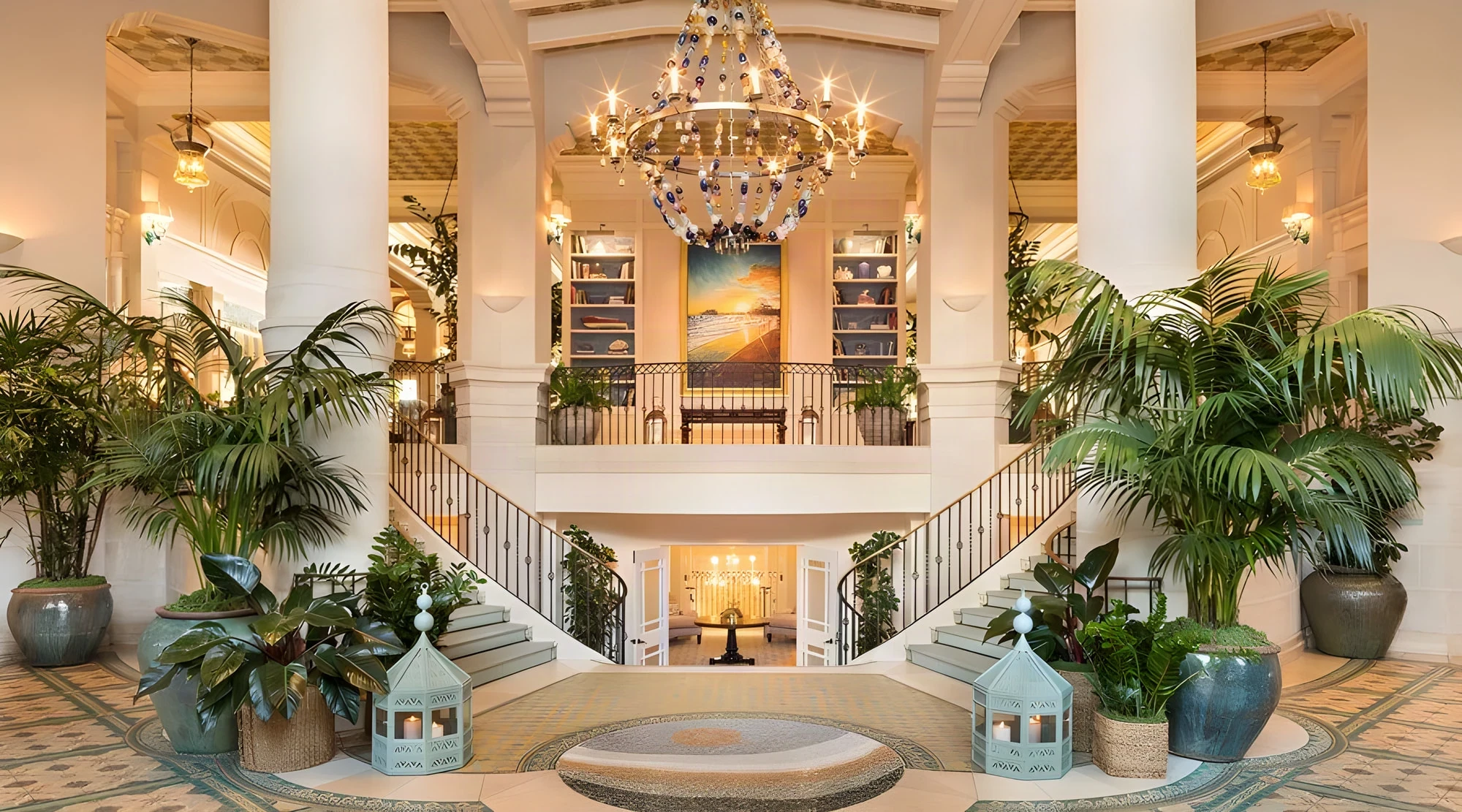 Casa del Mar hotel lobby with twin curved staircases, a crystal chandelier and potted palms