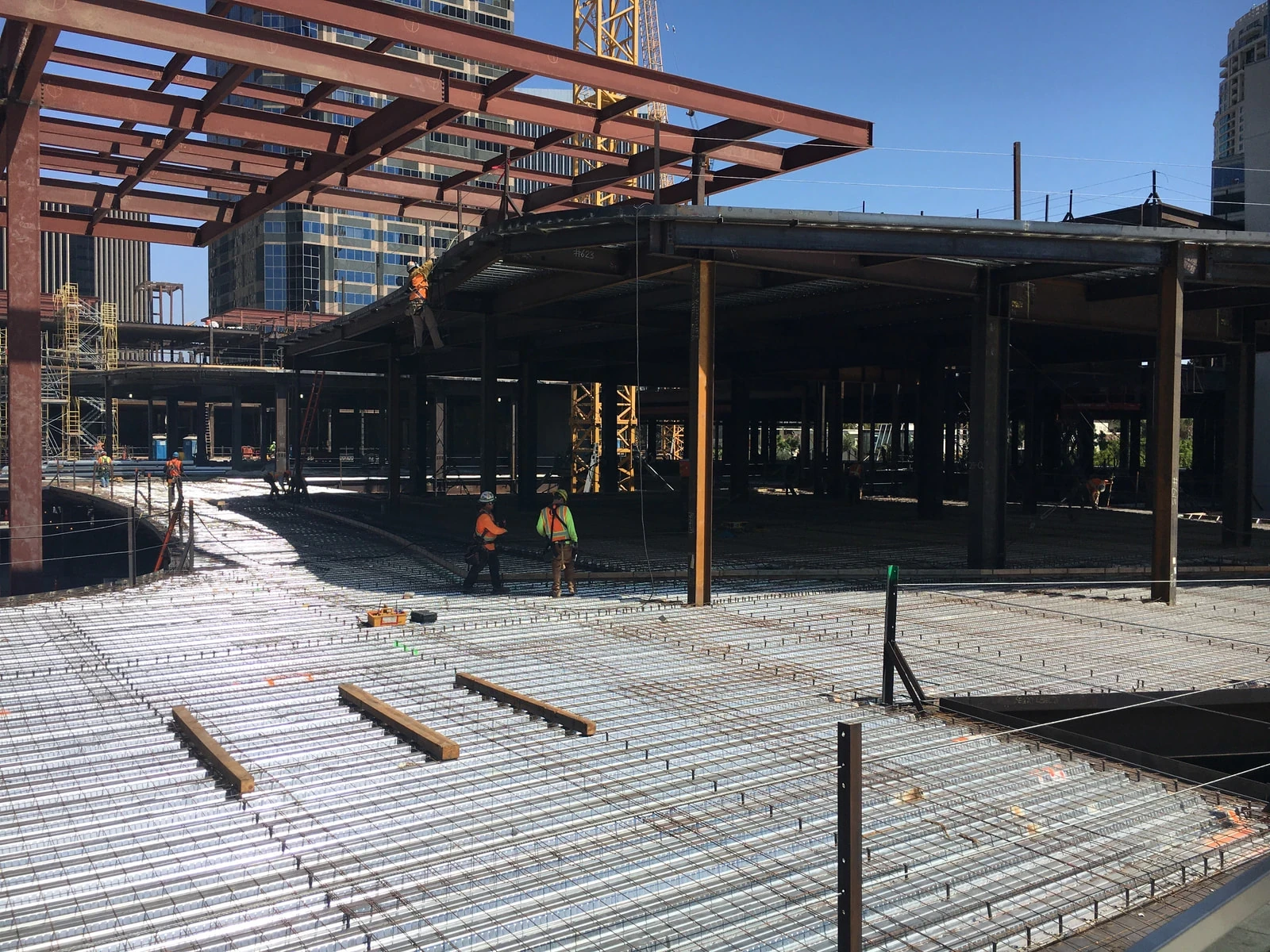 Ironworkers placing deck reinforcement under a downtown steel canopy