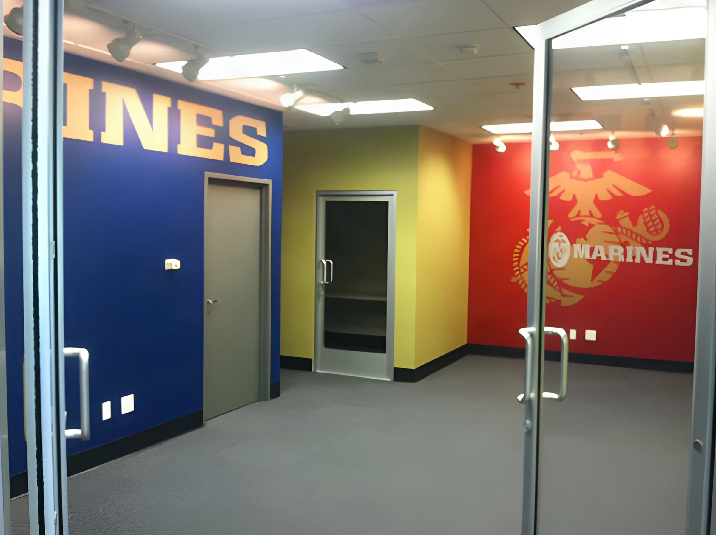 Marines office with a blue lettered wall and a red emblem wall behind glass doors