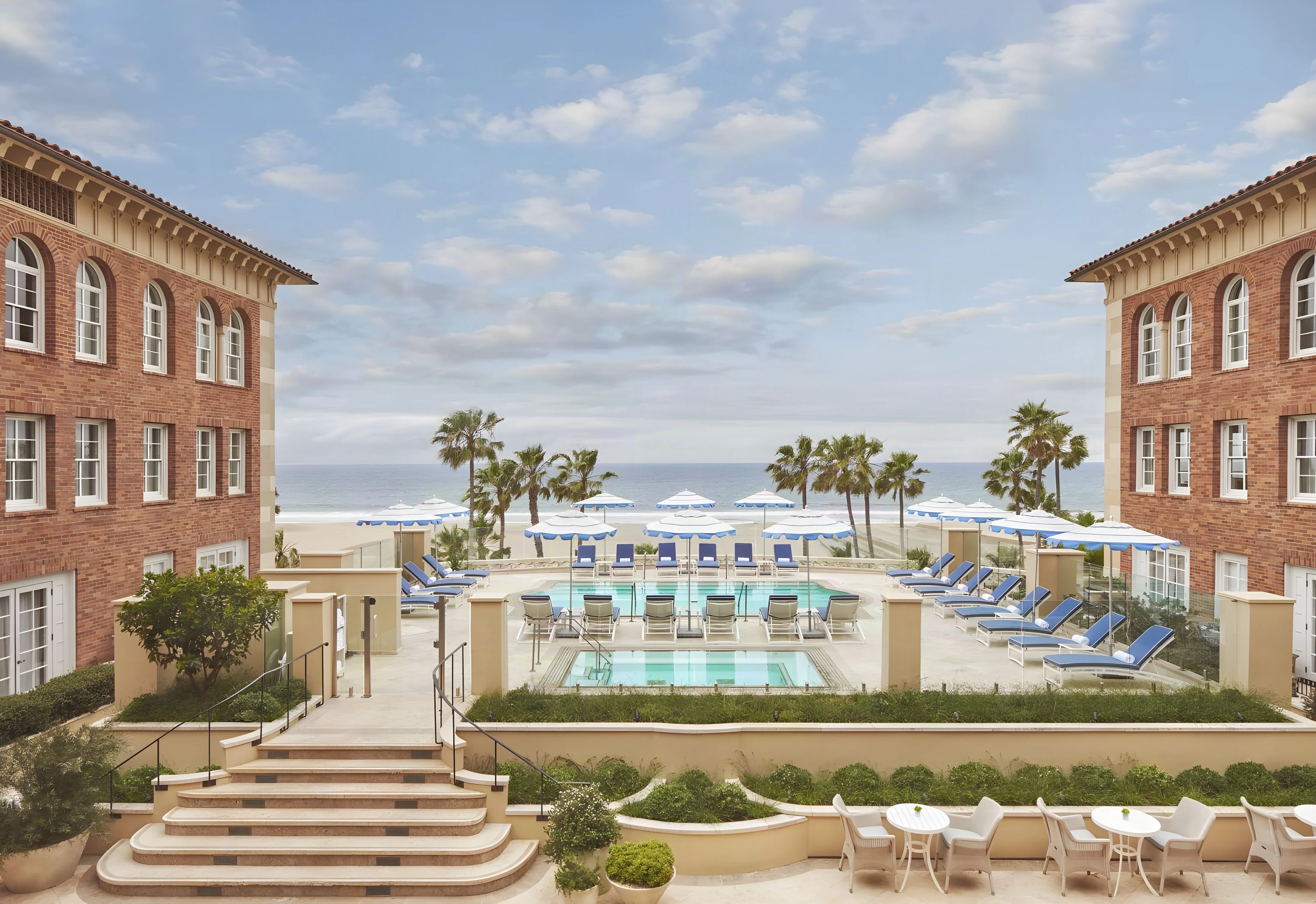 Brick wings of the Casa del Mar hotel framing its pool courtyard, with the Pacific Ocean beyond