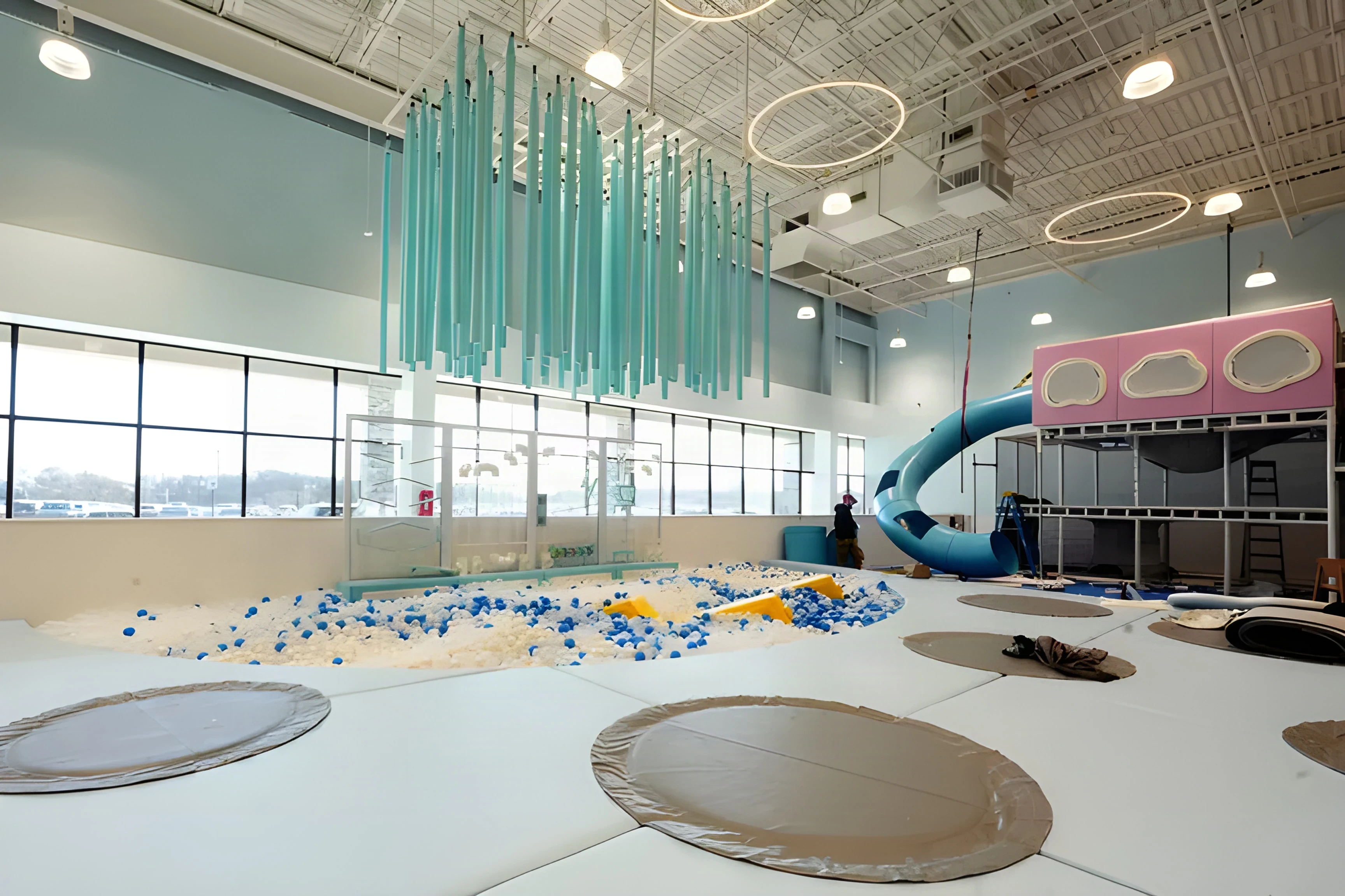 High-bay Cloudbound hall with a ball pit, hanging ribbons and a spiral tube slide