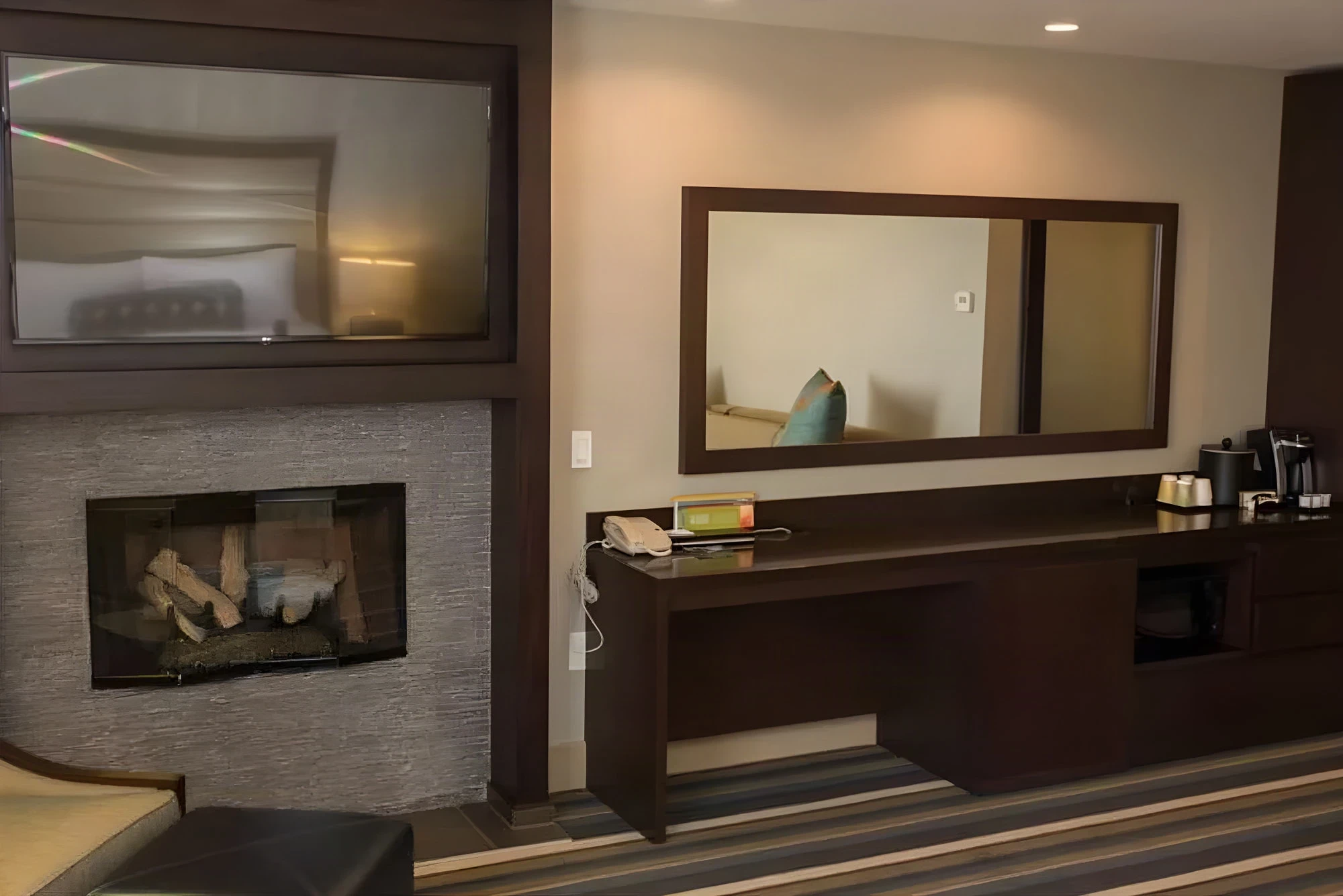 Suite fireplace wall and dark wood desk under a mirror at Hilton Garden Inn Montebello