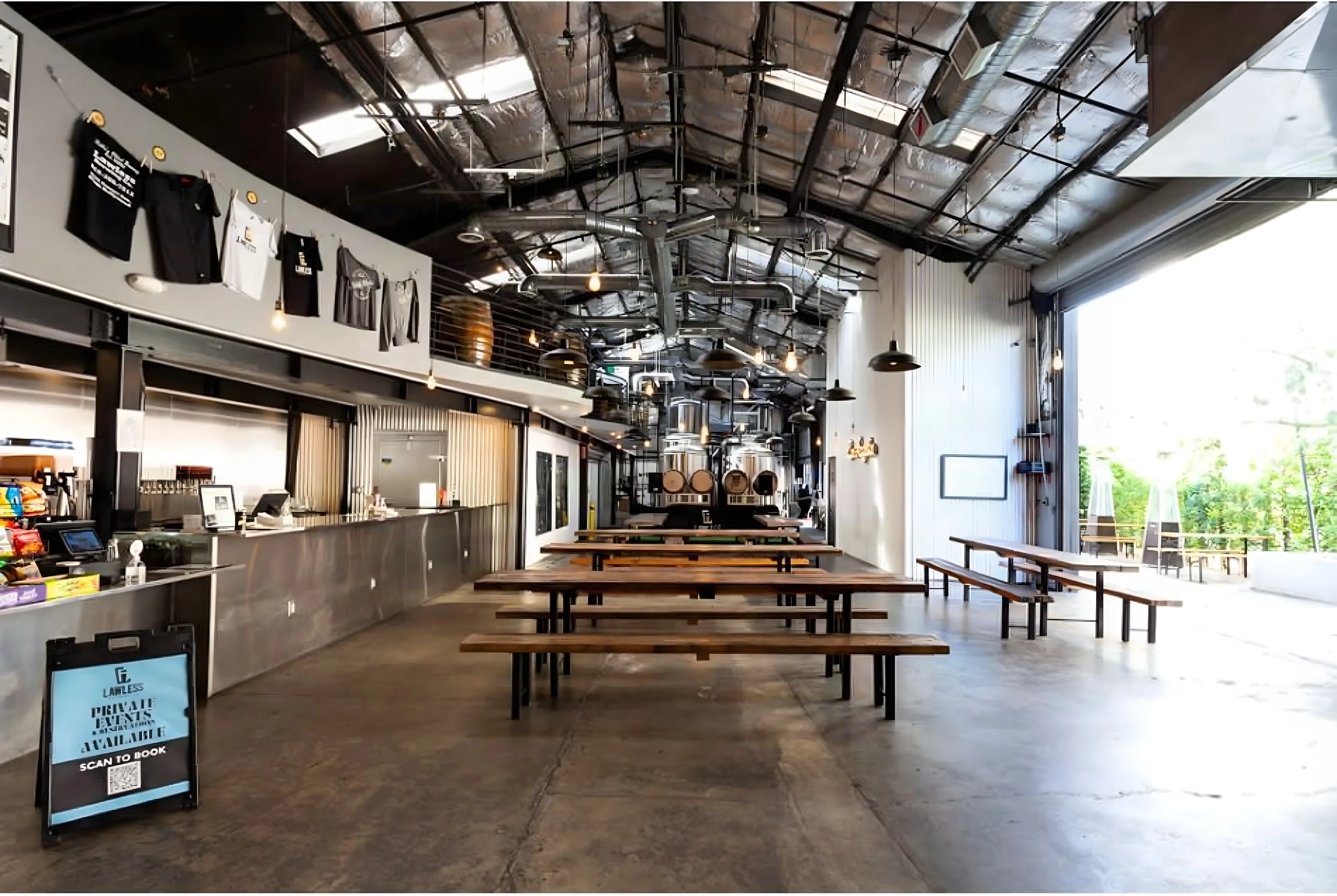 Lawless Brewing Co. taproom with long timber tables, a service counter and a roll-up door open to the garden
