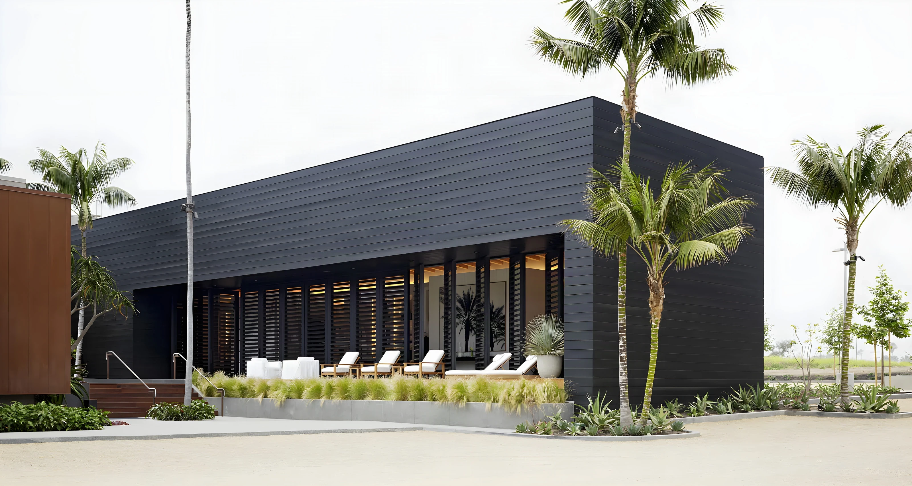Black timber pavilion framed by palms and native grasses at Malibu Lumber Yard