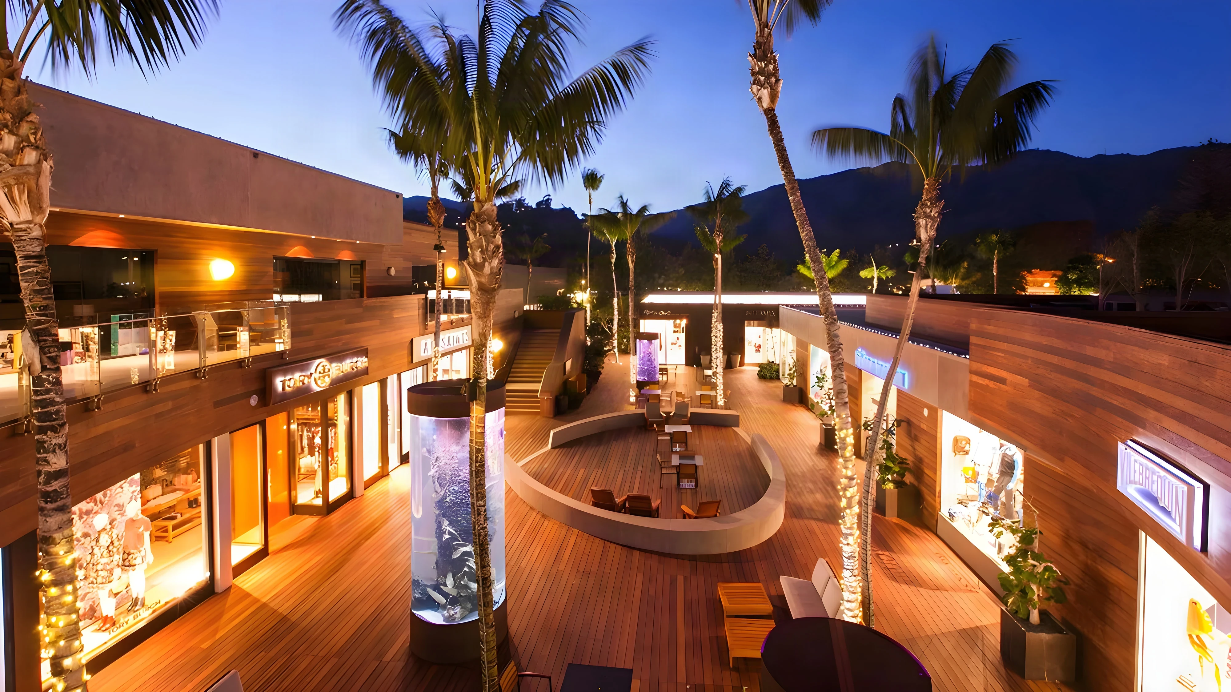 Malibu Lumber Yard plaza at dusk with ipe decking, glass railings and a lit aquarium column