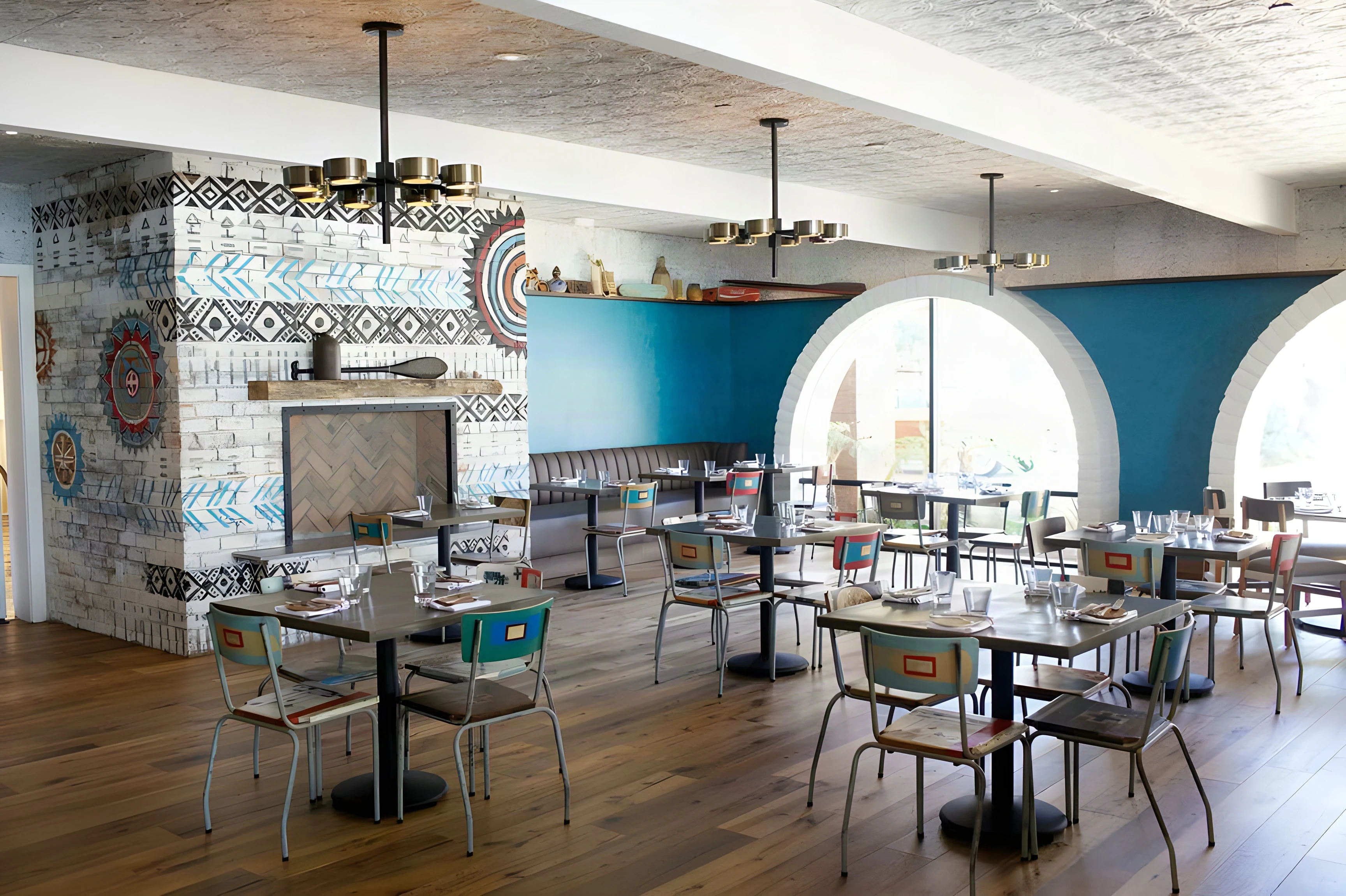 The Outpost dining room with a patterned tile column, arched windows and teal walls