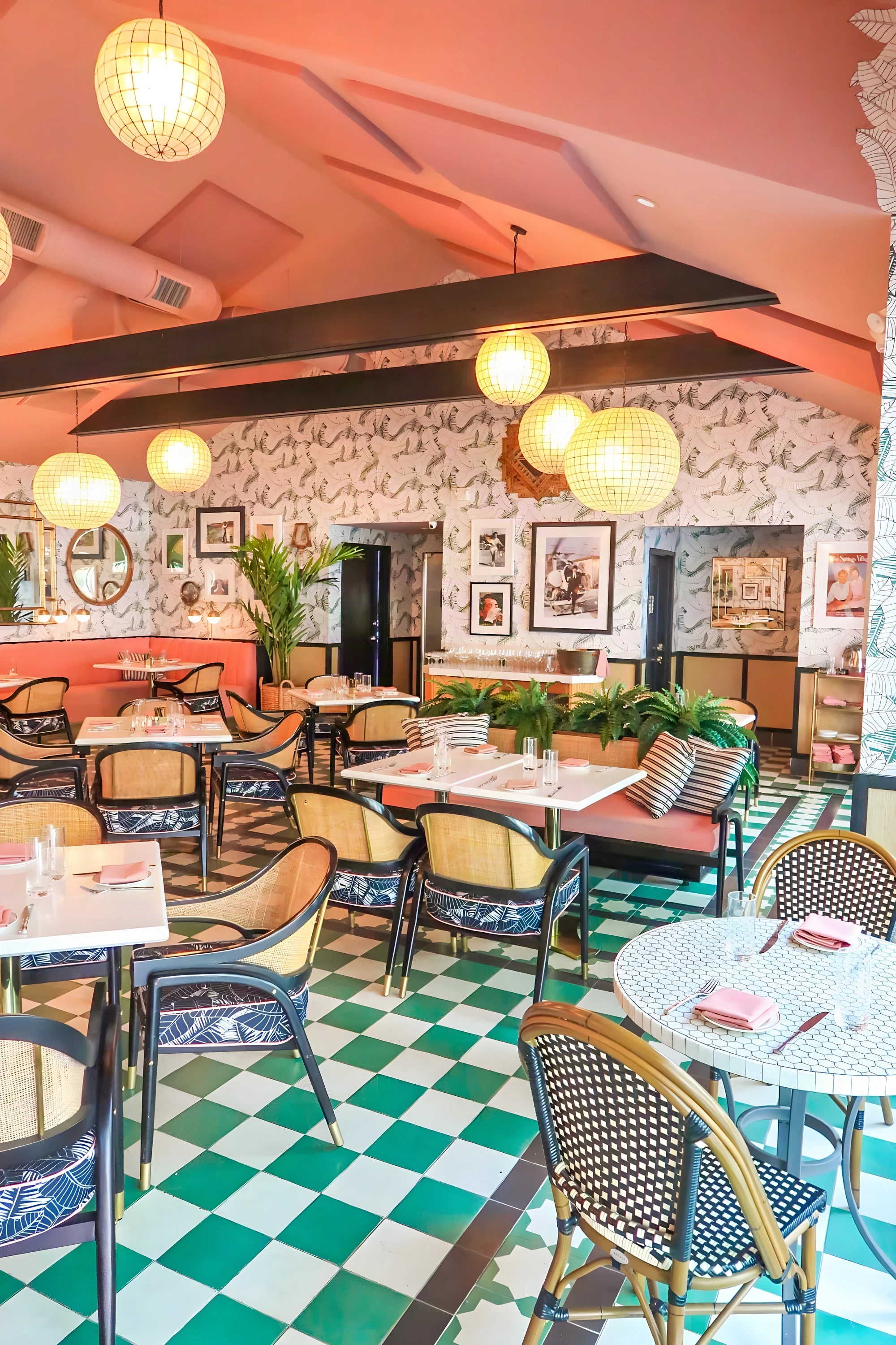 Green and white checkerboard floor and blue rattan chairs under pink beams at The Pink Cabana