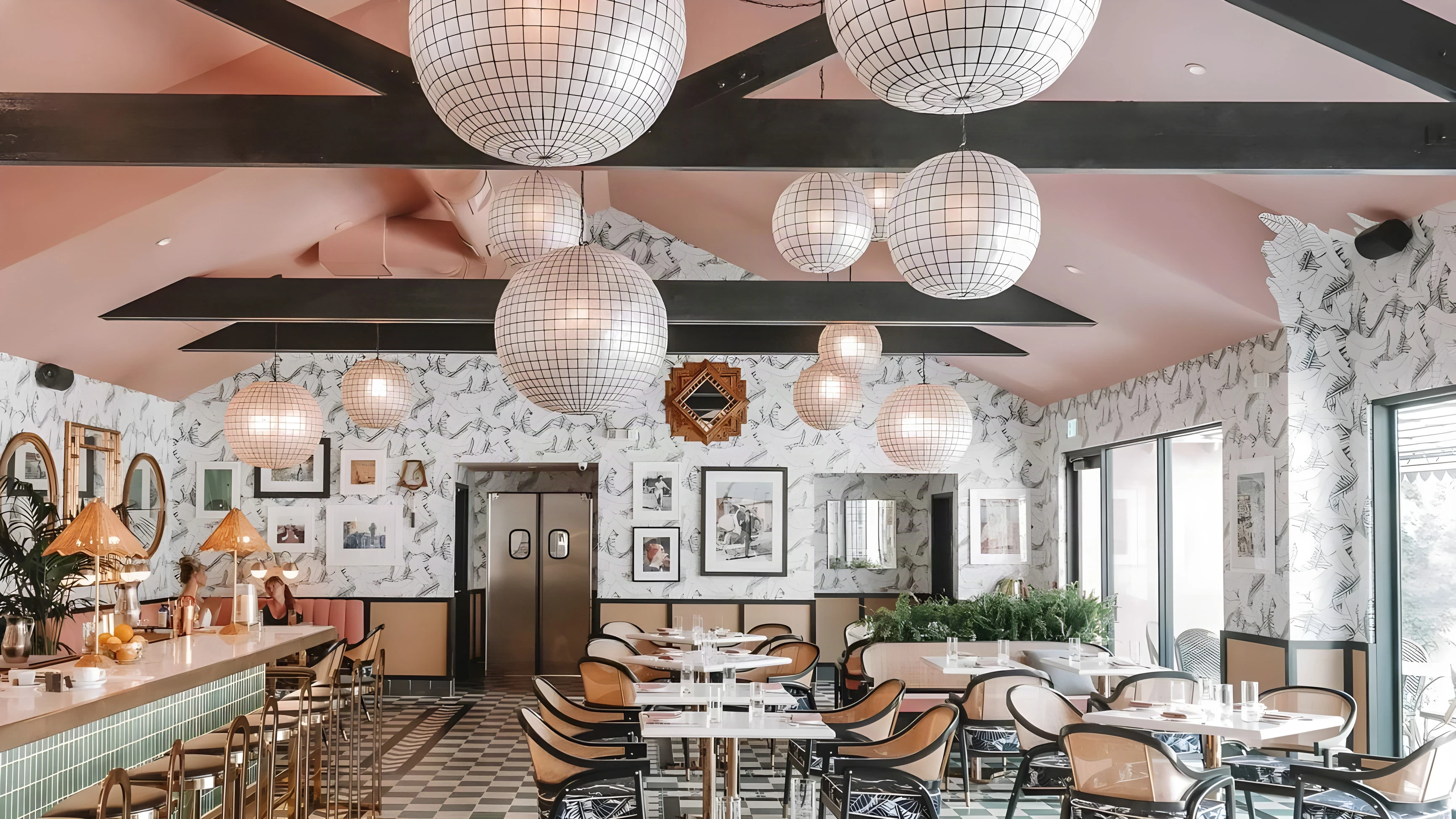 The Pink Cabana dining room with rattan pendants, a green tile bar and patterned wallpaper
