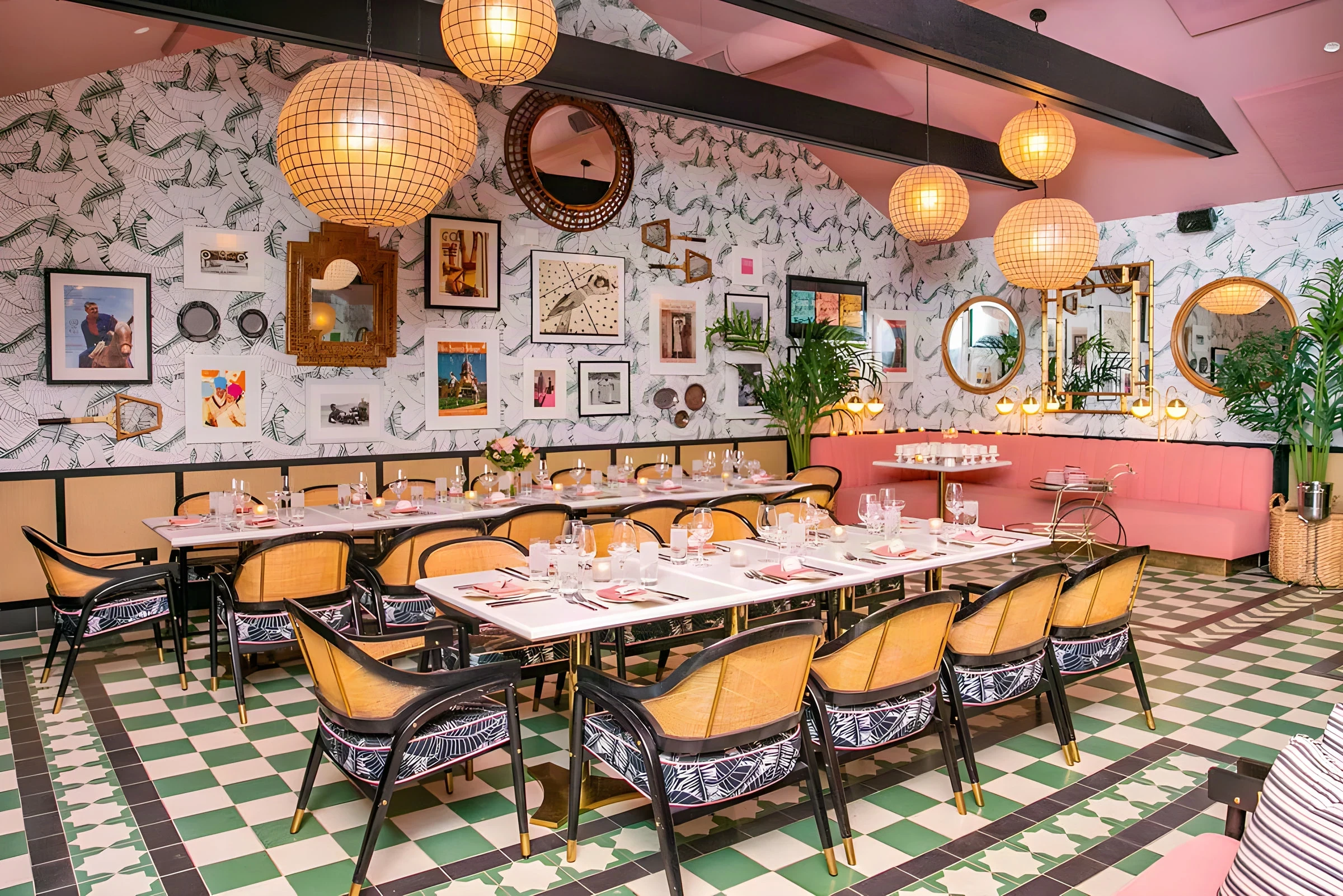 Long dining room at The Pink Cabana with a framed gallery wall, rattan chairs and a pink banquette