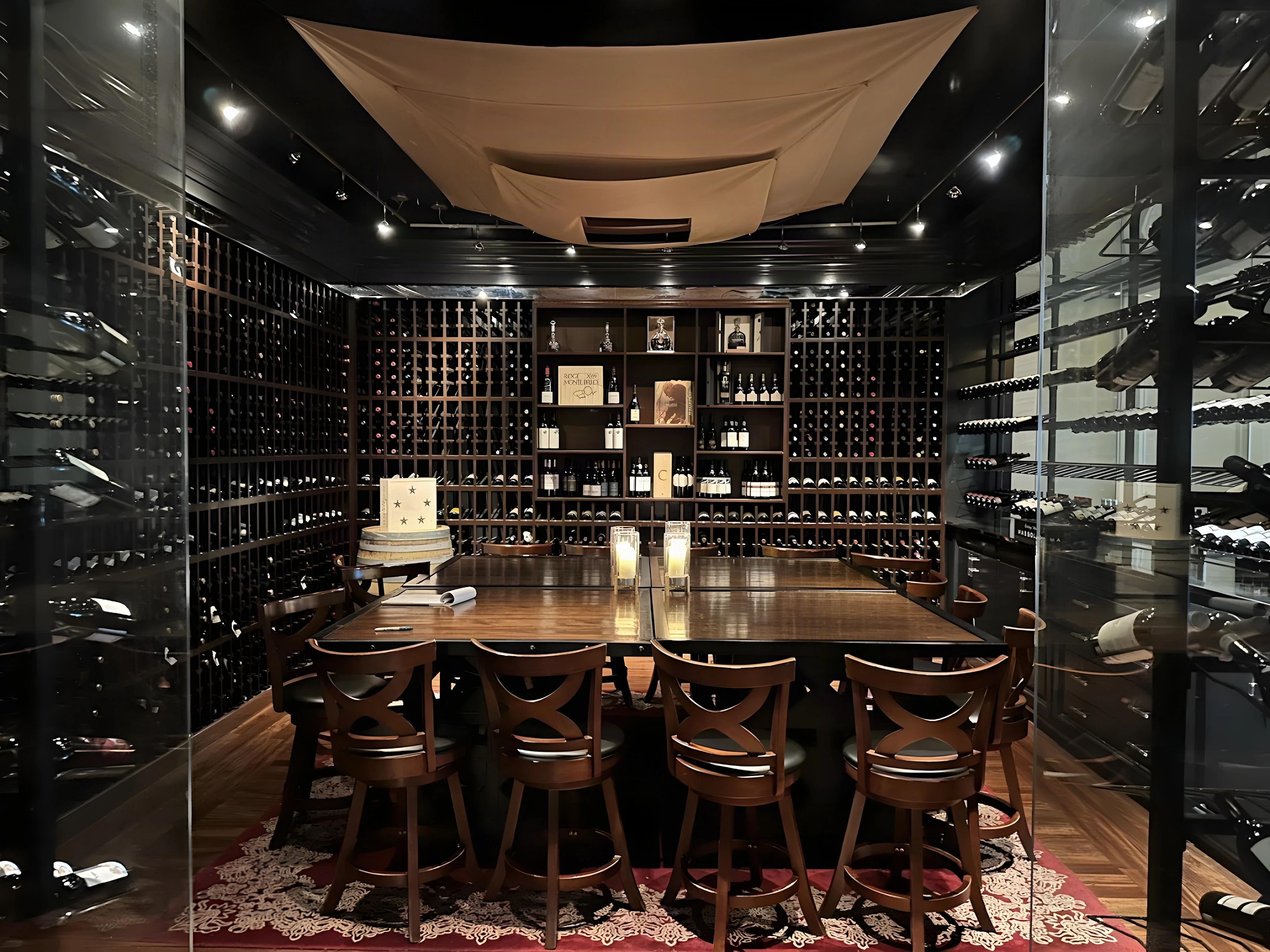 Royce Wine Room seen through its all-glass walls, with a draped ceiling, wine racks and a long dining table