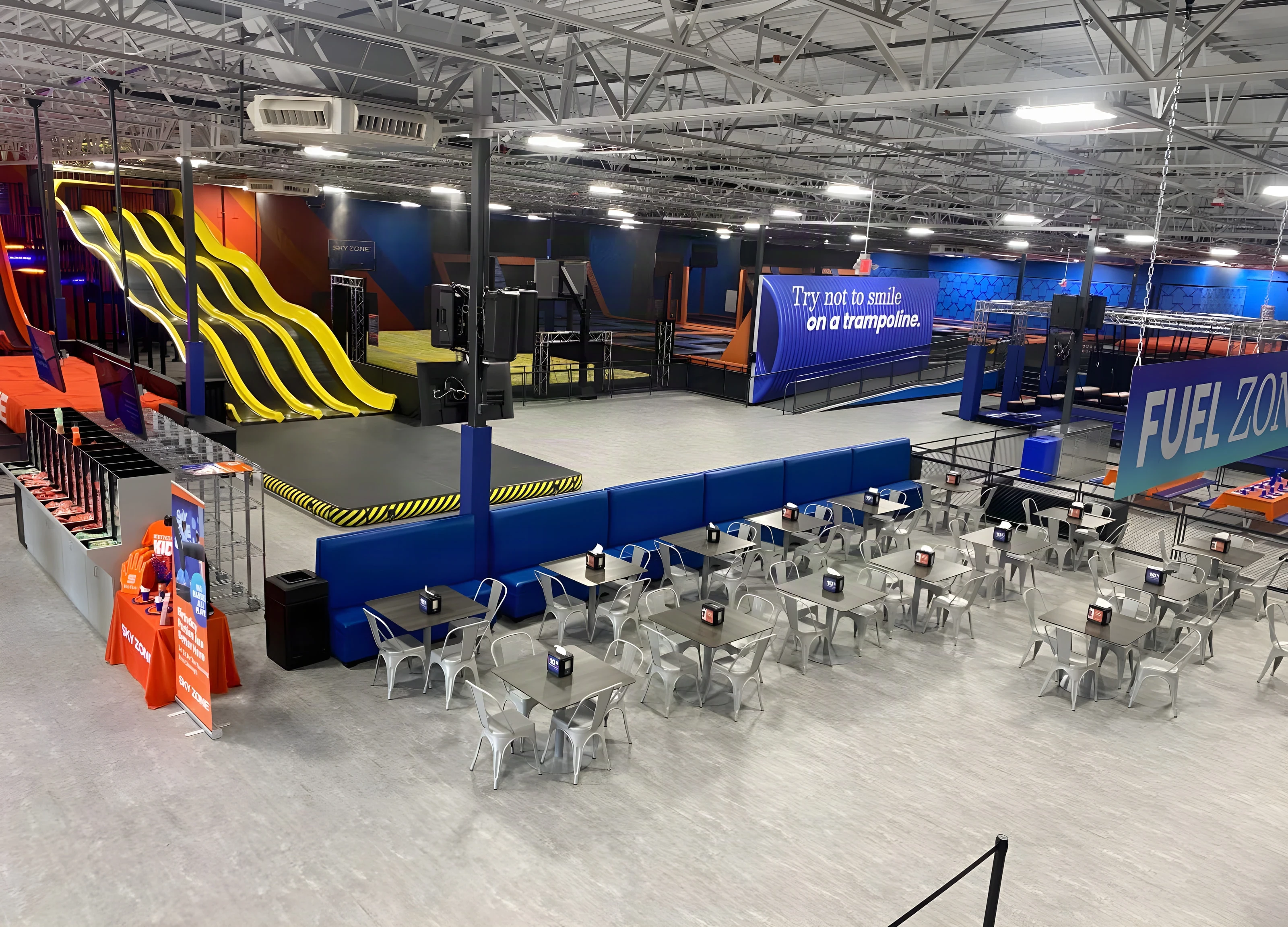 Yellow wave slides and café seating by the Fuel Zone at Sky Zone Frisco