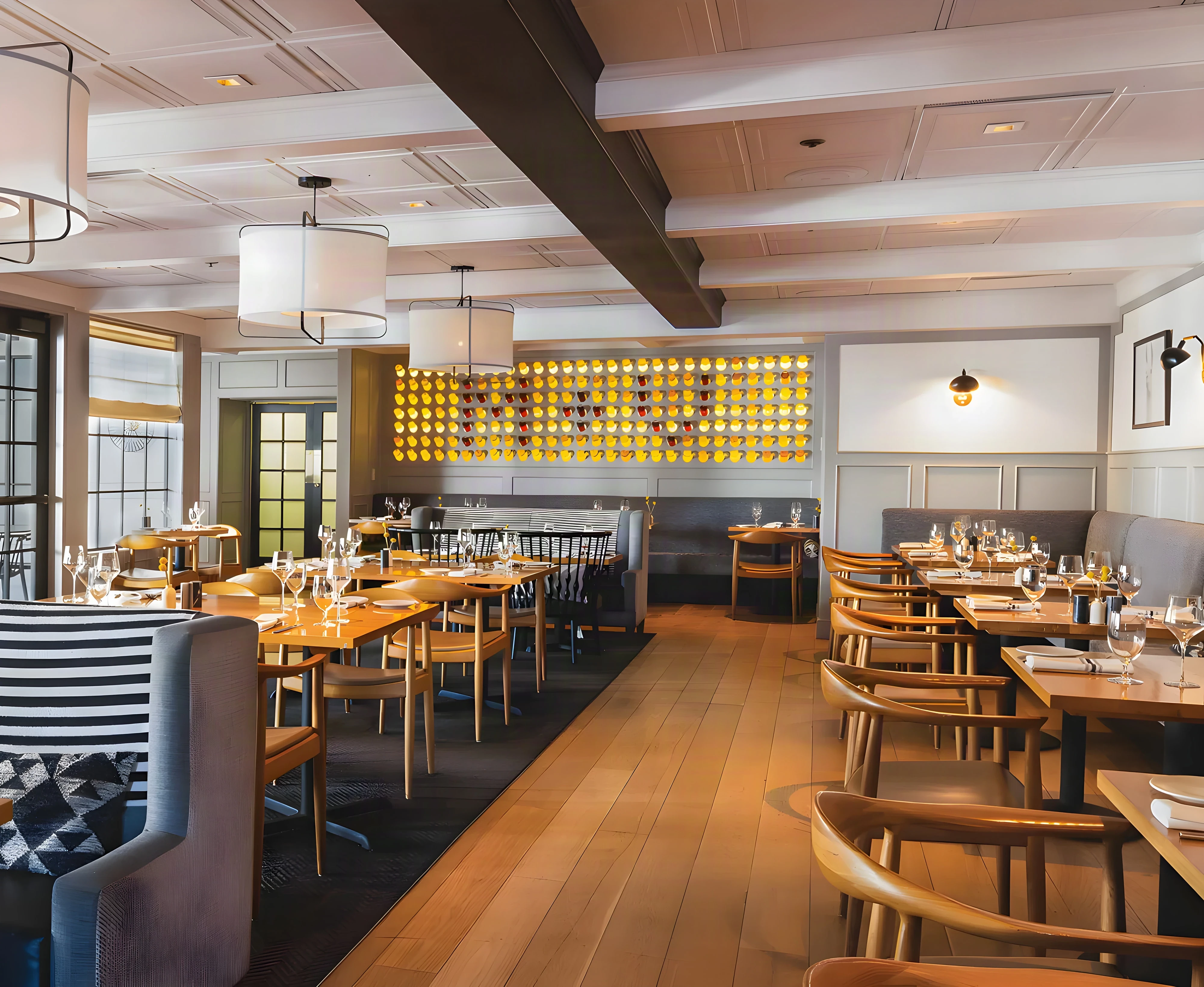 Mad & Vin dining room with grey banquettes, long oak tables and a glowing wall of wine bottles